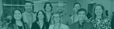 A group of smiling people in front of a conference banner.